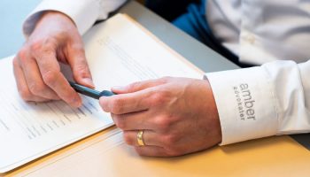 Advokathand med penna, i skjorta med logotyp